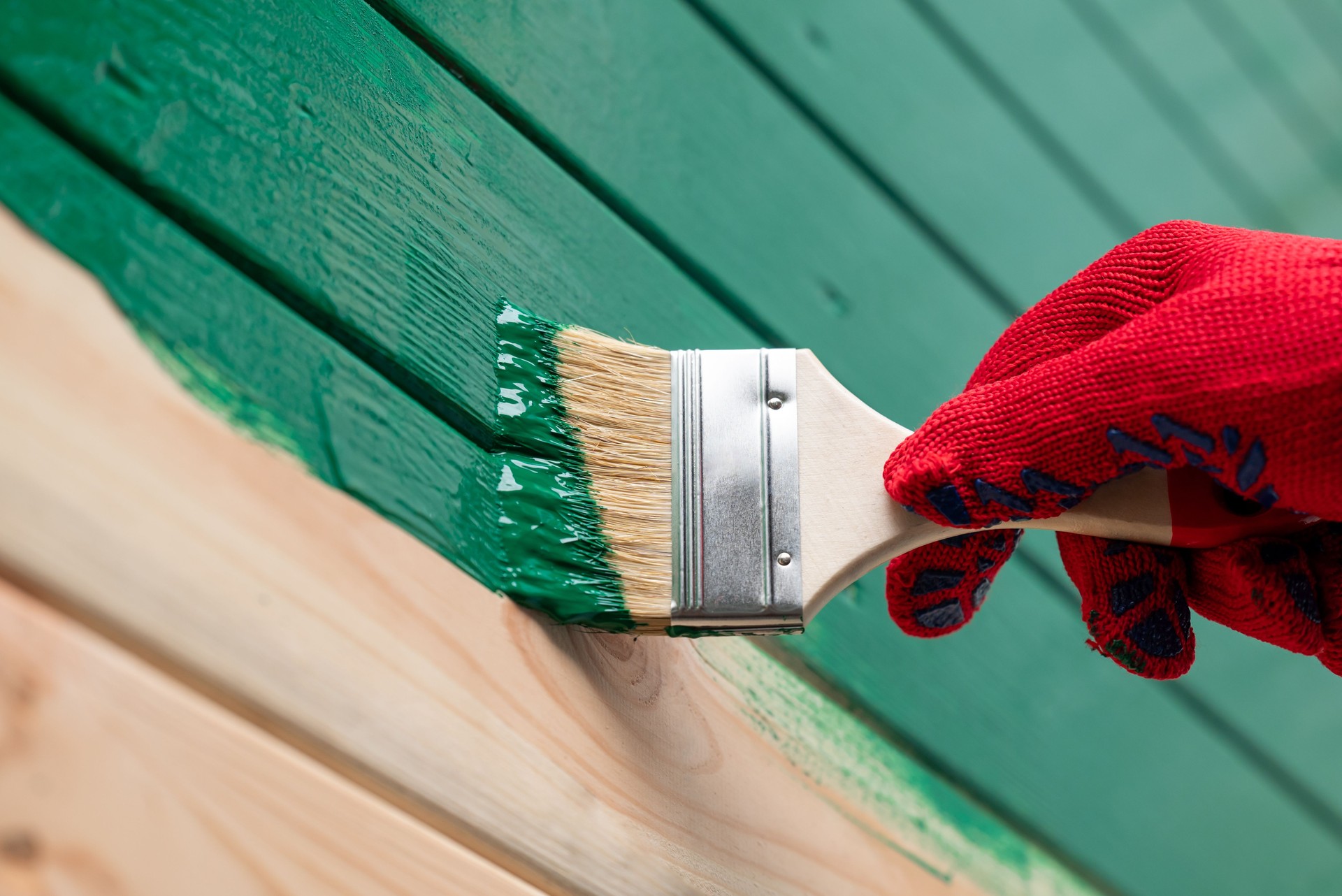 Close up of hand painting wooden wall with a brush